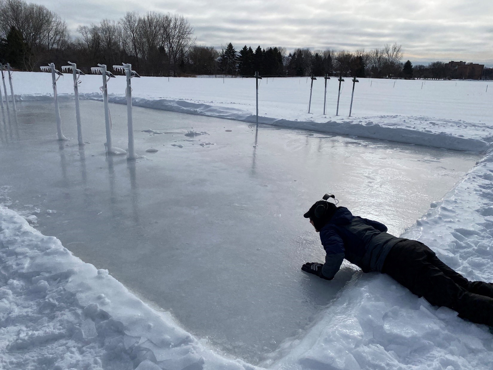 person lying on created ice patch on research plots in winter