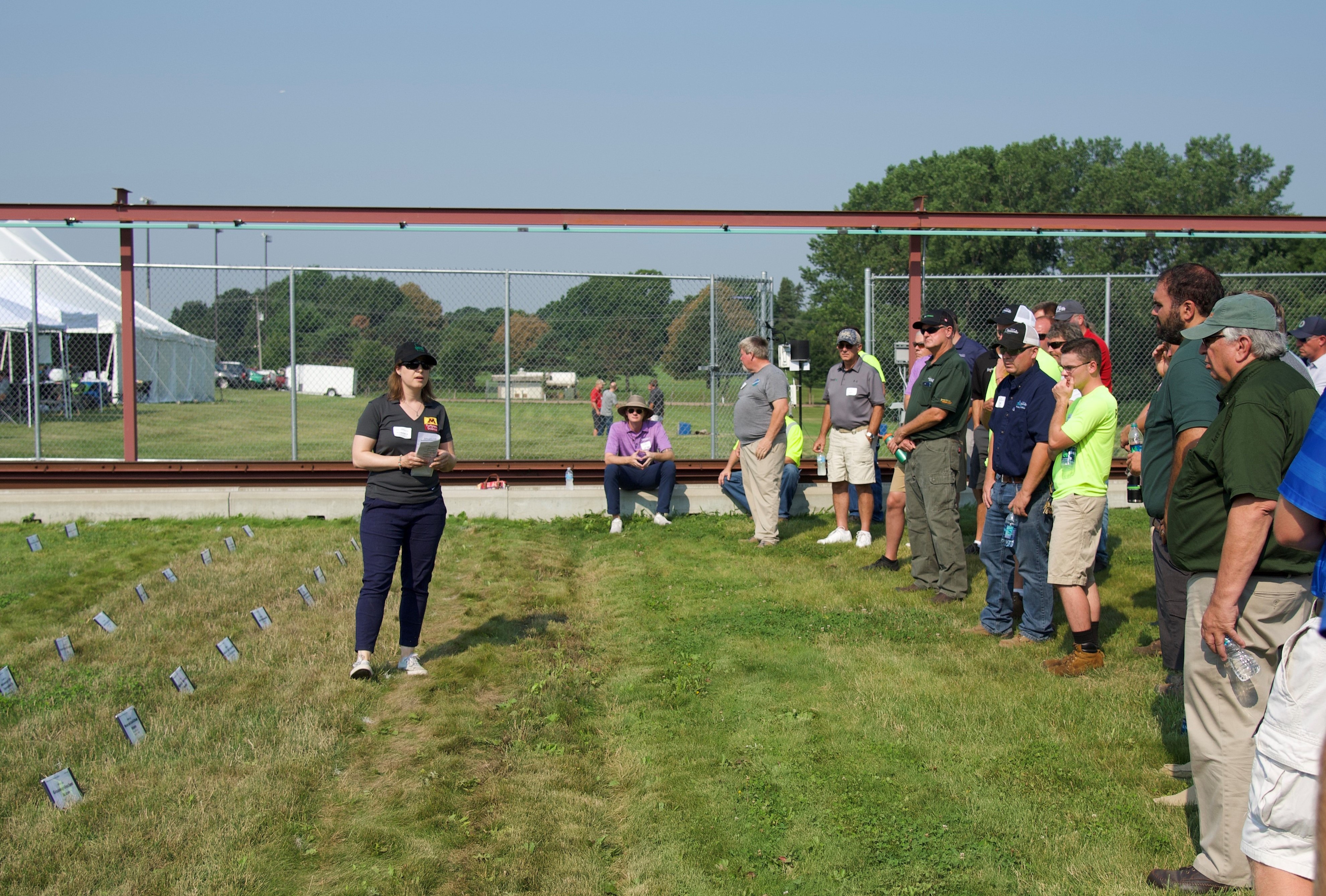 Woman giving a presentation to crowd in front of turf research plots