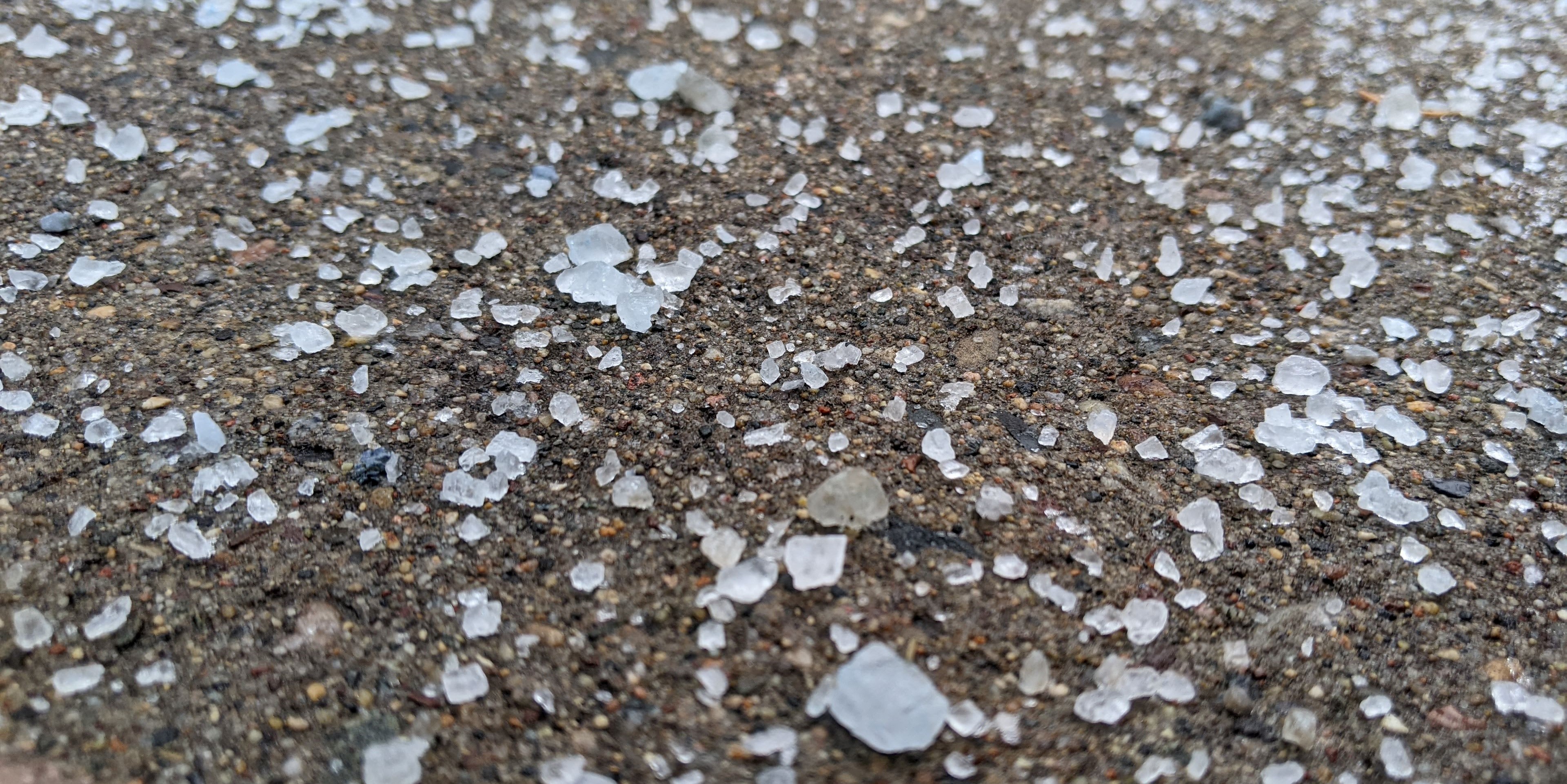 A closeup of deicing salt on a sidewalk in winter