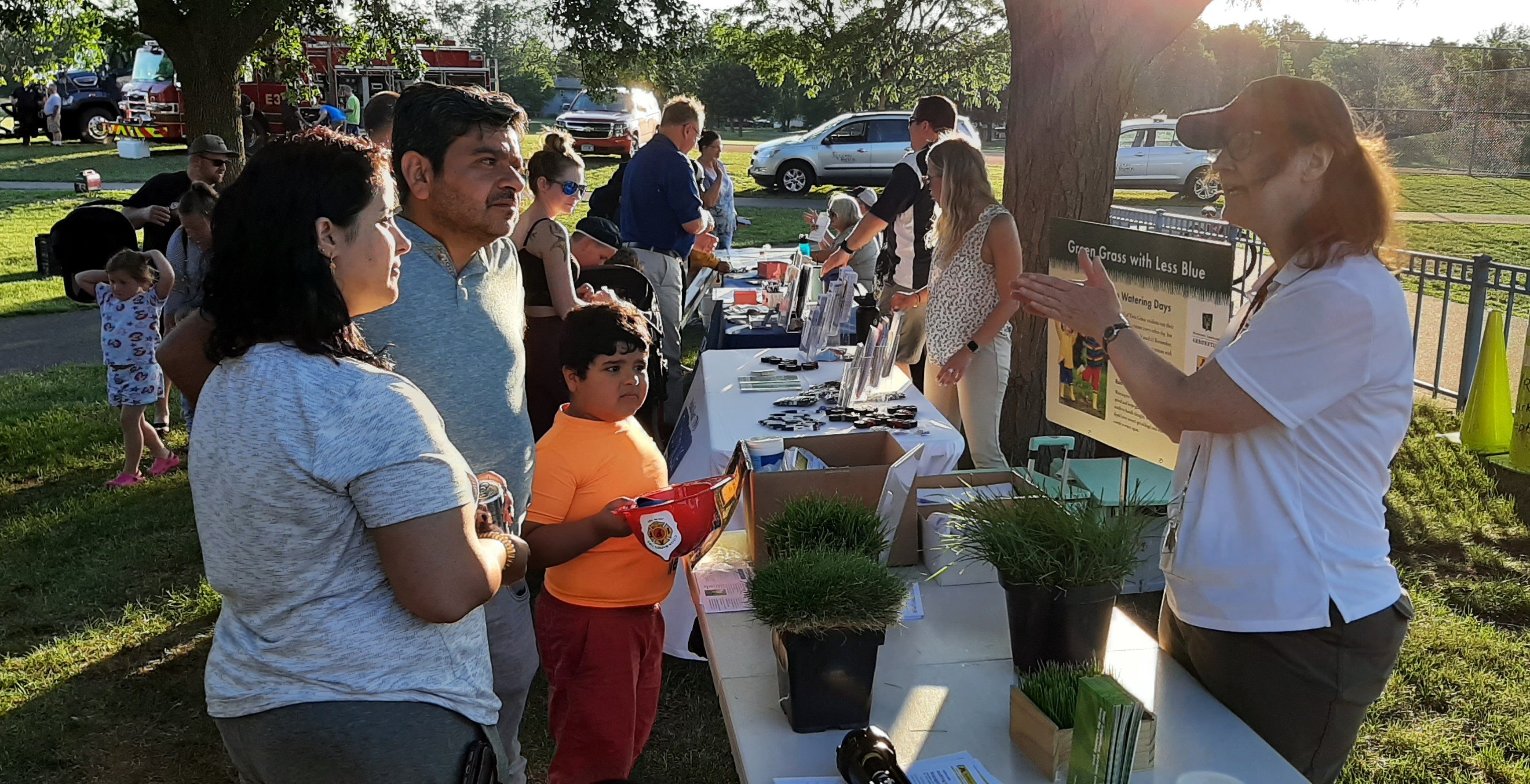 a woman explaining lawn care to a family of three at an outdoor educational event