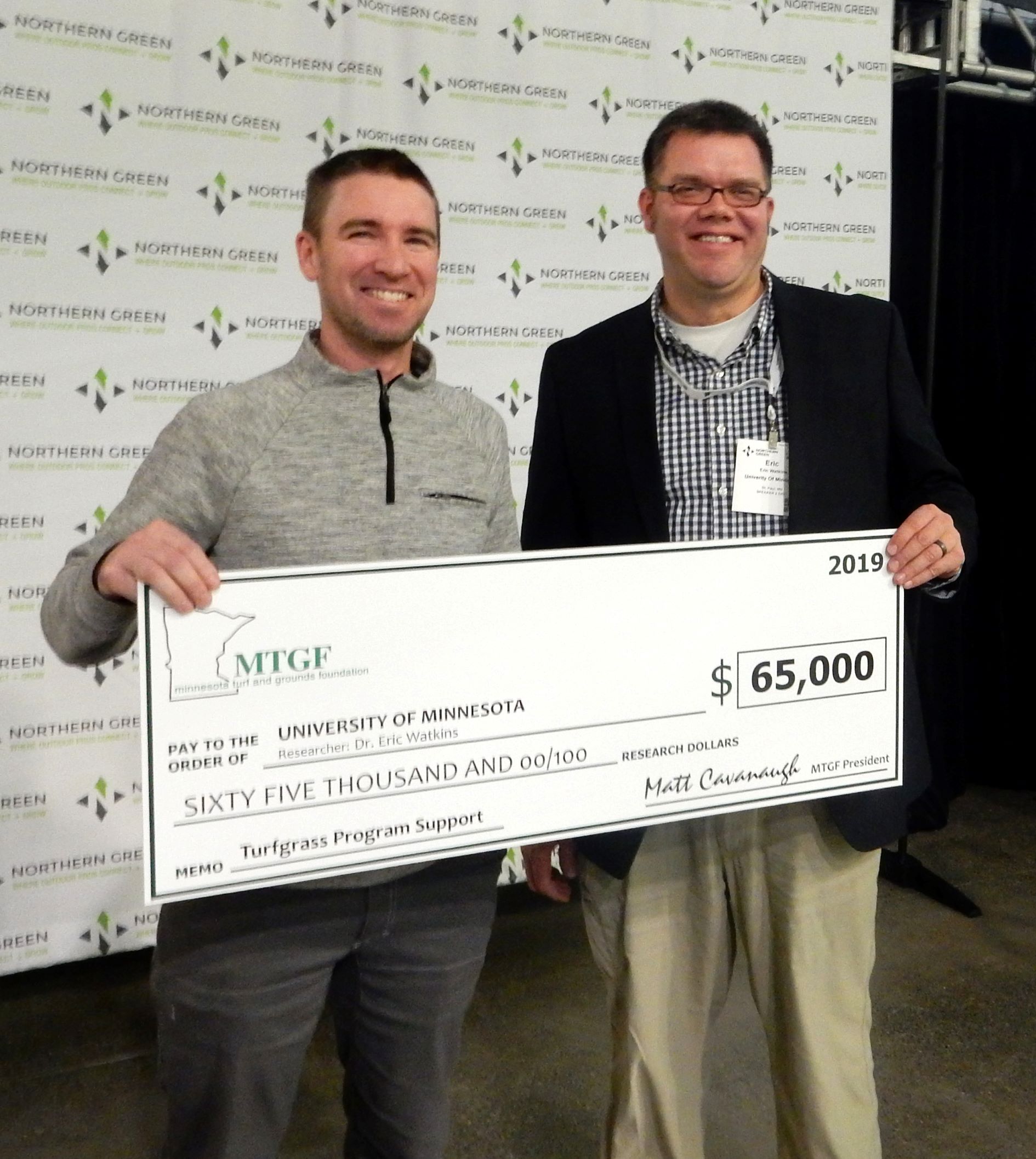 two men holding a novelty large-size check