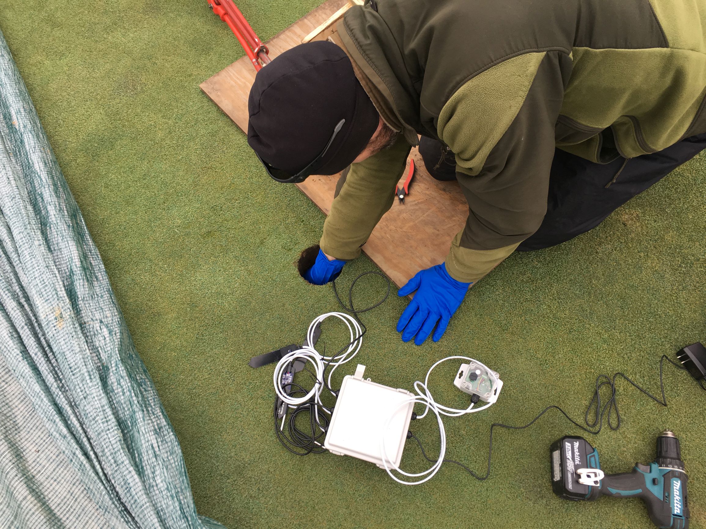 man installing sensor equipment on a golf course green