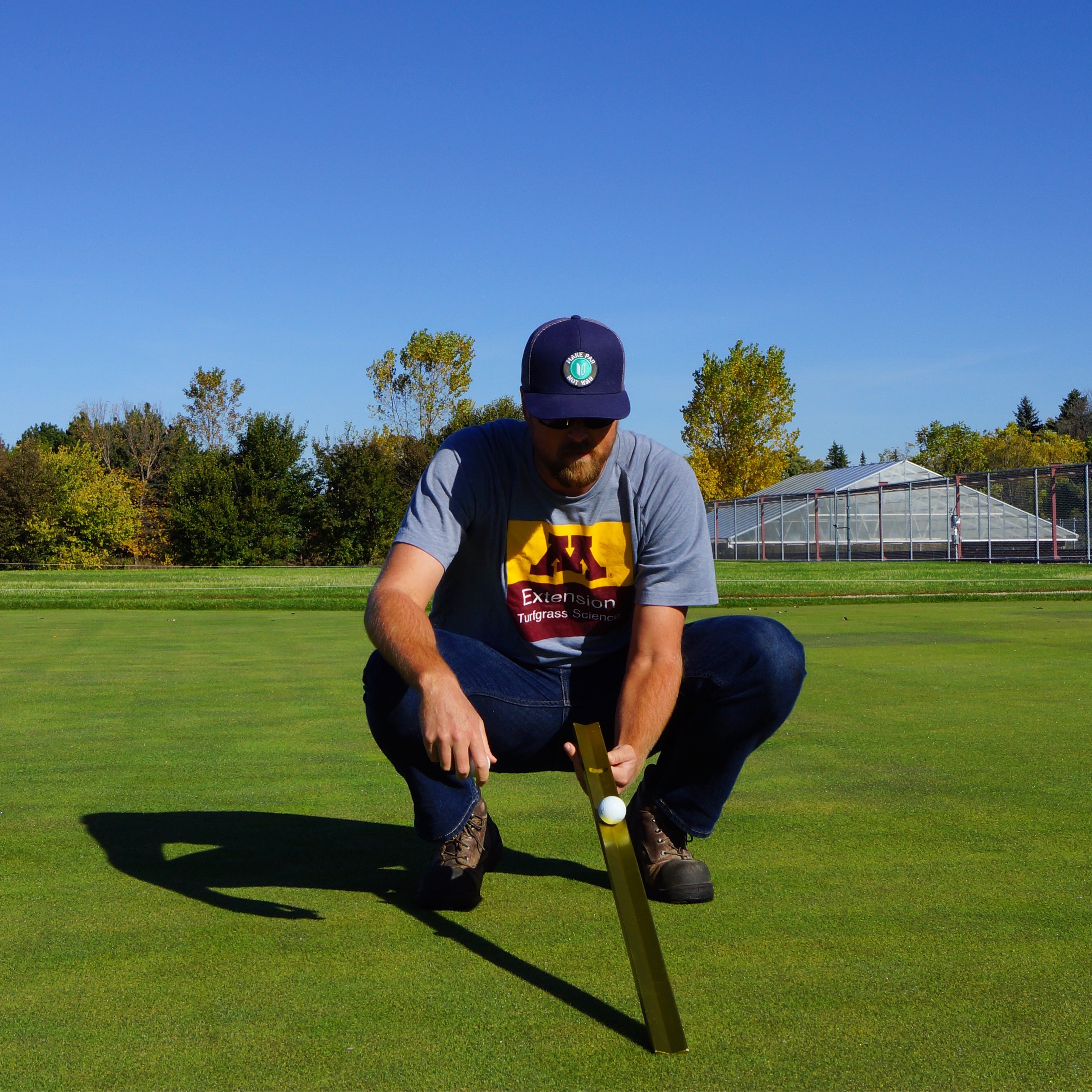 man with a stimpmeter tool on a golf course