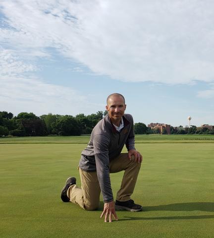 a man kneeling on a research putting green