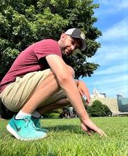 a man outstide crouching on turfgrass